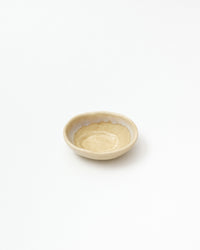 A small handmade ceramic bowl with a textured, speckled beige exterior and a smooth, slightly scalloped off-white interior, photographed on a seamless white background.