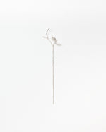 A delicate silver-toned metal branch or vine accessory with a long stem and small leaf-like details at the top, photographed against a plain white background.