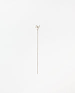 A delicate silver stick with a small leaf-shaped top, photographed vertically against a clean, solid white background.