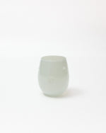 A small, rounded translucent glass cup with a pale mint green color, photographed against a seamless white background.