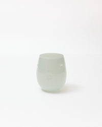 A small, rounded translucent glass cup with a pale mint green color, photographed against a seamless white background.