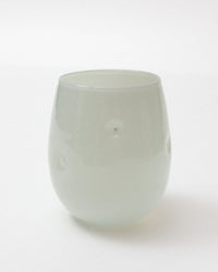 A translucent pale green glass tumbler with a rounded shape and small circular cutouts on the sides, photographed on a clean white background.