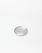 A single small circular silver-toned metal tray with a smooth, reflective surface, centered on a plain white background.