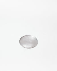 A single small circular silver-toned metal tray with a smooth, reflective surface, centered on a plain white background.