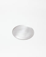 A minimalist, round silver tray with a brushed metal finish, centered on a clean white background.