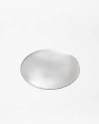 A single small circular silver-toned metal tray with a smooth, reflective surface, centered on a plain white background.