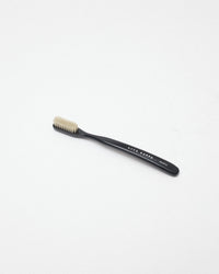 A single black toothbrush with beige bristles, featuring the brand name 'ACCA KAPPA' printed on the handle, set against a plain white background.