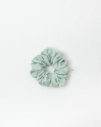 A melon green satin scrunchie centered on a clean white background.