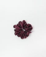 A single dark burgundy satin scrunchie with a soft sheen, photographed from directly above on a clean white background.