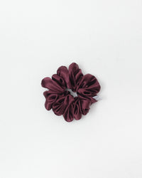 A single dark burgundy satin scrunchie with a soft sheen, photographed from directly above on a clean white background.