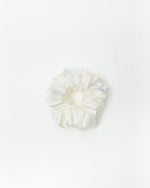 A single white satin hair scrunchie centered on a clean white background.