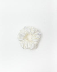 A single white satin hair scrunchie centered on a clean white background.