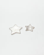 A pair of textured silver star-shaped ceramic items on a clean white background.