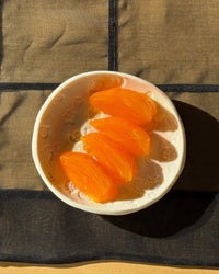 White bowl with persimmon slices on a black cloth