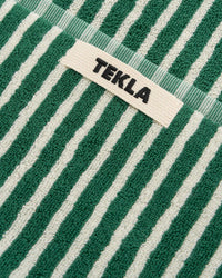 Close-up of green and white striped fabric with 'Tekla' label.